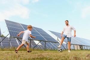 padre y hijo jugando fútbol americano en jardín de solar panelado foto