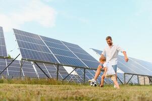 Father and son playing football in garden of solar paneled photo