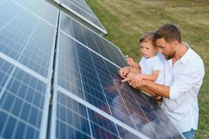contento padre y su pequeño hijo son caminando cerca el solar paneles el concepto de verde energía. foto