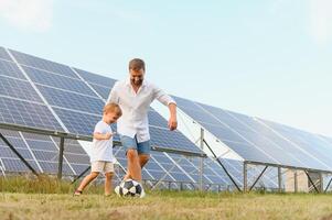 padre y hijo jugando fútbol americano en jardín de solar panelado foto