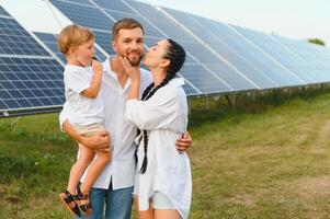 el concepto de verde energía. contento familia caminando y teniendo divertido en solar panel campo. verde energía. foto