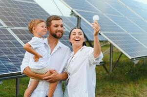 el concepto de renovable energía. joven contento familia cerca solar paneles foto