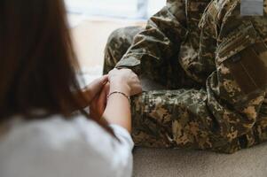 cropped shot of soldier and psychiatrist holding hands during therapy session. photo