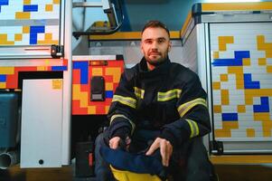 Portrait of male firefighter in uniform at fire station photo