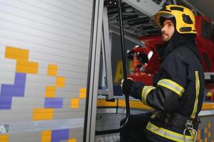 Fireman wearing protective uniform standing in fire department at fire station photo