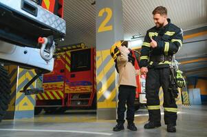 un bombero tomar un pequeño niño chico a salvar a él. fuego motor coche en antecedentes foto