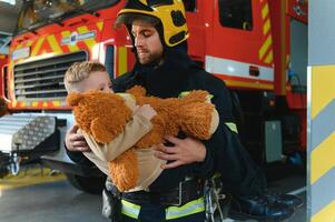 Firefighter holding child boy to save him in fire and smoke,Firemen rescue the boys from fire photo