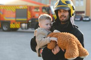 Firefighter holding child boy to save him in fire and smoke,Firemen rescue the boys from fire photo