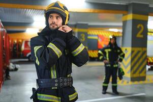 Fireman wearing protective uniform standing in fire department at fire station photo