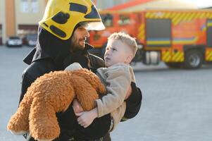 Firefighter holding child boy to save him in fire and smoke,Firemen rescue the boys from fire photo