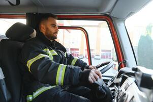 Side view of firefighter in protective uniform driving fire engine photo