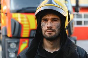 fireman in protective uniform standing near fire engine on station photo