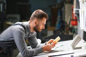 Print house worker controlling printing process quality and checking colors with magnifying glass photo