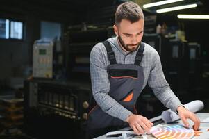 Man working in printing house with paper and paints photo