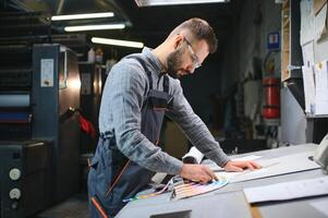 Print house worker controlling printing process quality and checking colors with magnifying glass photo