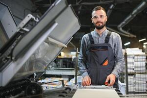 Man working in printing house with paper and paints photo