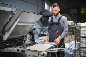 Graphic engineer or worker checking imprint quality in modern print shop photo