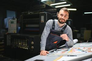 Print house worker controlling printing process quality and checking colors with magnifying glass photo