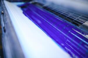 blue ink on rollers of industrial offset printer during work in typography workshop photo