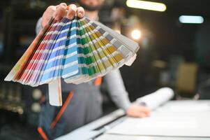 Typographer standing with color swatches at the printing manufacturing photo