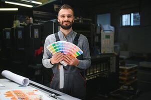 Typographer standing with color swatches at the printing manufacturing photo