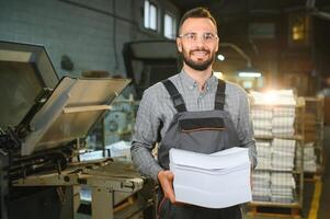 Man working in printing house with paper and paints photo