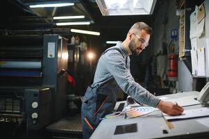 Print house worker controlling printing process quality and checking colors with magnifying glass photo