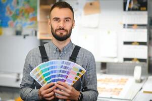 Man working in printing house with paper and paints photo