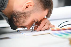 Print house worker controlling printing process quality and checking colors with magnifying glass photo