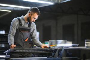 Man working in printing house with paper and paints photo