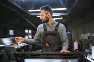 Man working in printing house with paper and paints photo