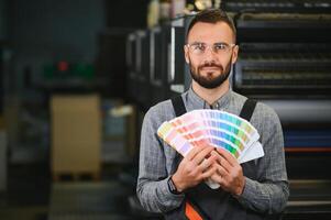 Man working in printing house with paper and paints photo