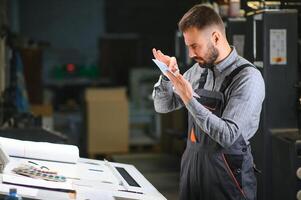 Graphic engineer or worker checking imprint quality in modern print shop photo