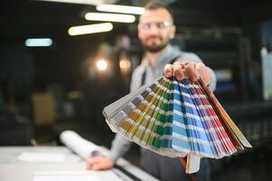 Man working in printing house with paper and paints photo