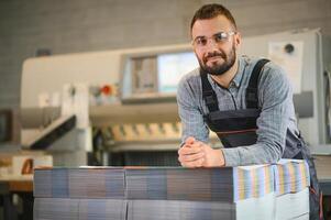 Man working in printing house with paper and paints photo