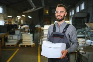 Man working in printing house with paper and paints photo
