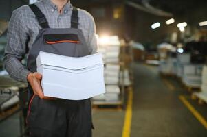 Close up of man putting stack of paper in printing machine at publishing shop, copy space photo