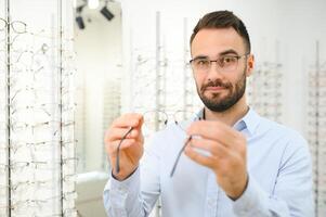 joven hombre elegir gafas a óptico tienda foto