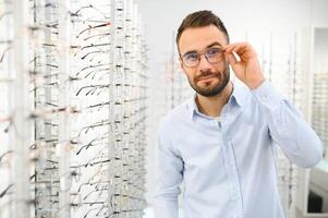 hombre elige lentes para visión corrección en un oftalmología salón. lentes para visión corrección foto