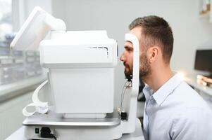 Handsome young man is checking the eye vision in modern ophthalmology clinic. Patient in ophthalmology clinic photo