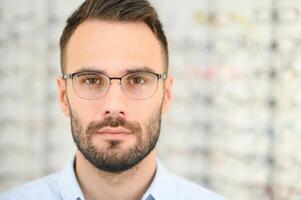 Man choosing glasses in eyewear store photo