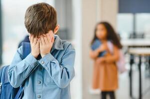 upset boy at school covering his face with his hands. Bullying at school photo