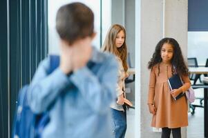 School friends bullying a sad boy in corridor at school photo