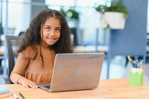 Smiling small African American girl watch video lesson on computer, homeschooling concept photo