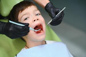 Cute boy smiling while teeth exam . Happy boy sitting in dentists chair and having check up teeth photo