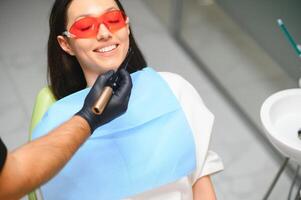 dentist curing the patient's teeth with ultraviolet lamp in his office photo