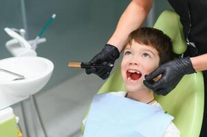 Dentist examining little boy's teeth in clinic photo