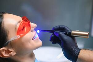 Young woman getting dental filling drying procedure with curing UV light at dental clinic photo