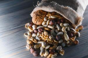 Wooden bowl with mixed nuts on rustic table top view. Healthy food and snack. photo