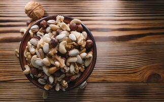 mezclado nueces en un cuenco en de madera mesa, parte superior ver con Copiar espacio. foto